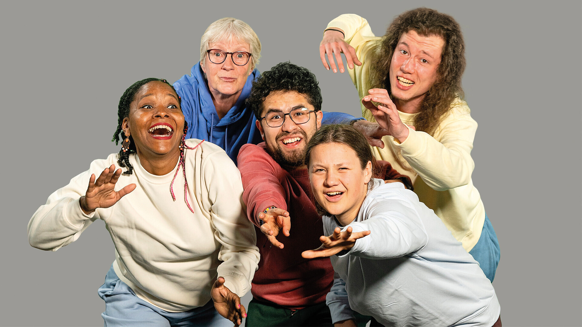KI generiert: Das Bild zeigt fünf fröhliche Personen in lässigen Outfits, die direkt in die Kamera blicken und freundliche Gesten machen. Die Gruppe wirkt dynamisch und lebensfroh.