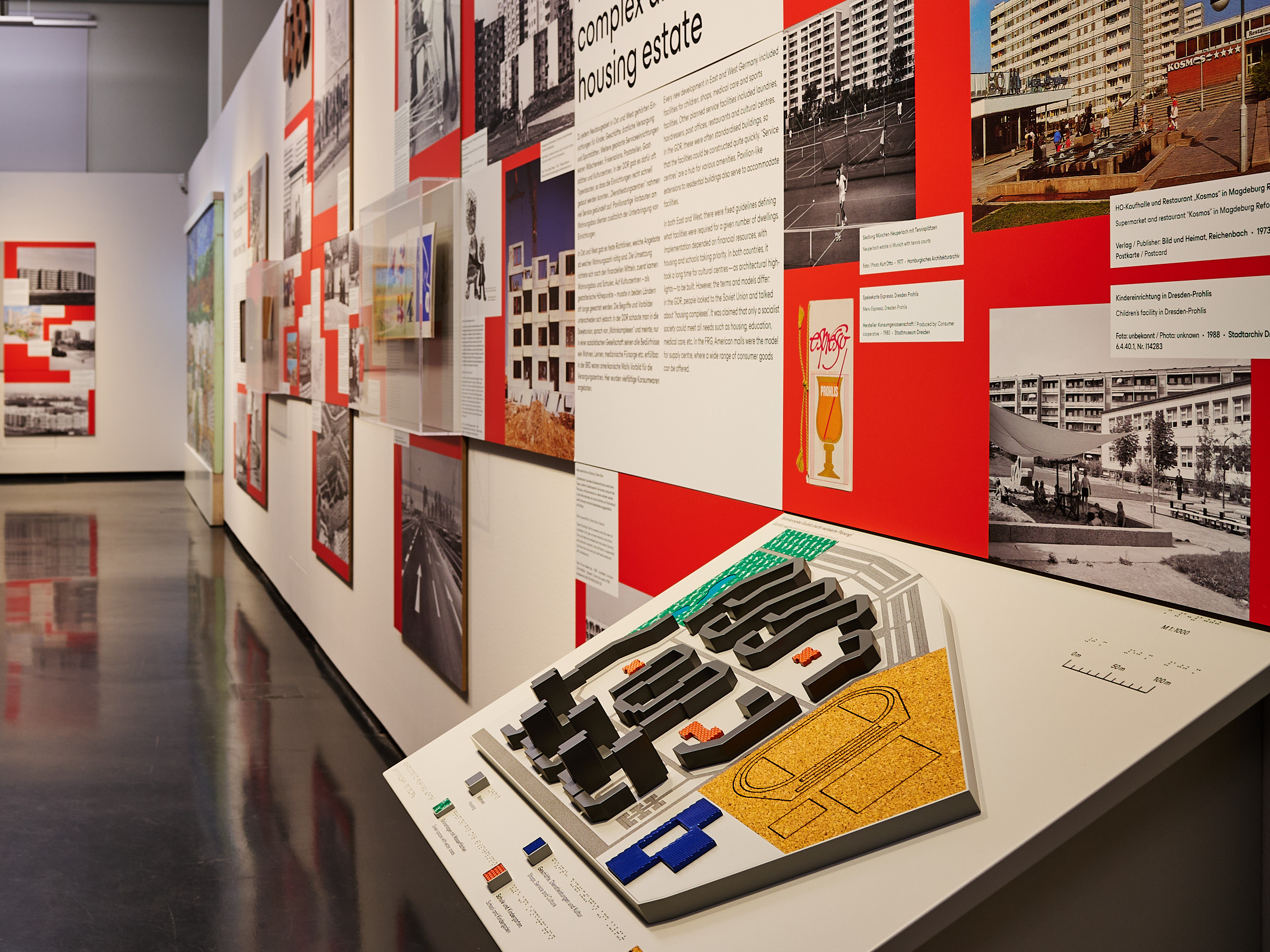 KI generiert: Das Bild zeigt eine Gruppe von Kindern, die auf einem Spielplatz spielen und durch eine bunt bemalte Mauer mit Kreisen krabbeln und klettern. Im Hintergrund sind große Wohngebäude zu sehen.