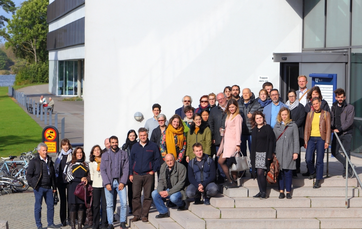 KI generiert: Das Bild zeigt eine Gruppe von Menschen, die gemeinsam auf einer Treppe draußen vor einem modernen Gebäude stehen. Es scheint eine Versammlung oder ein Gruppenfoto zu sein, möglicherweise im Rahmen einer Veranstaltung oder eines Seminars.